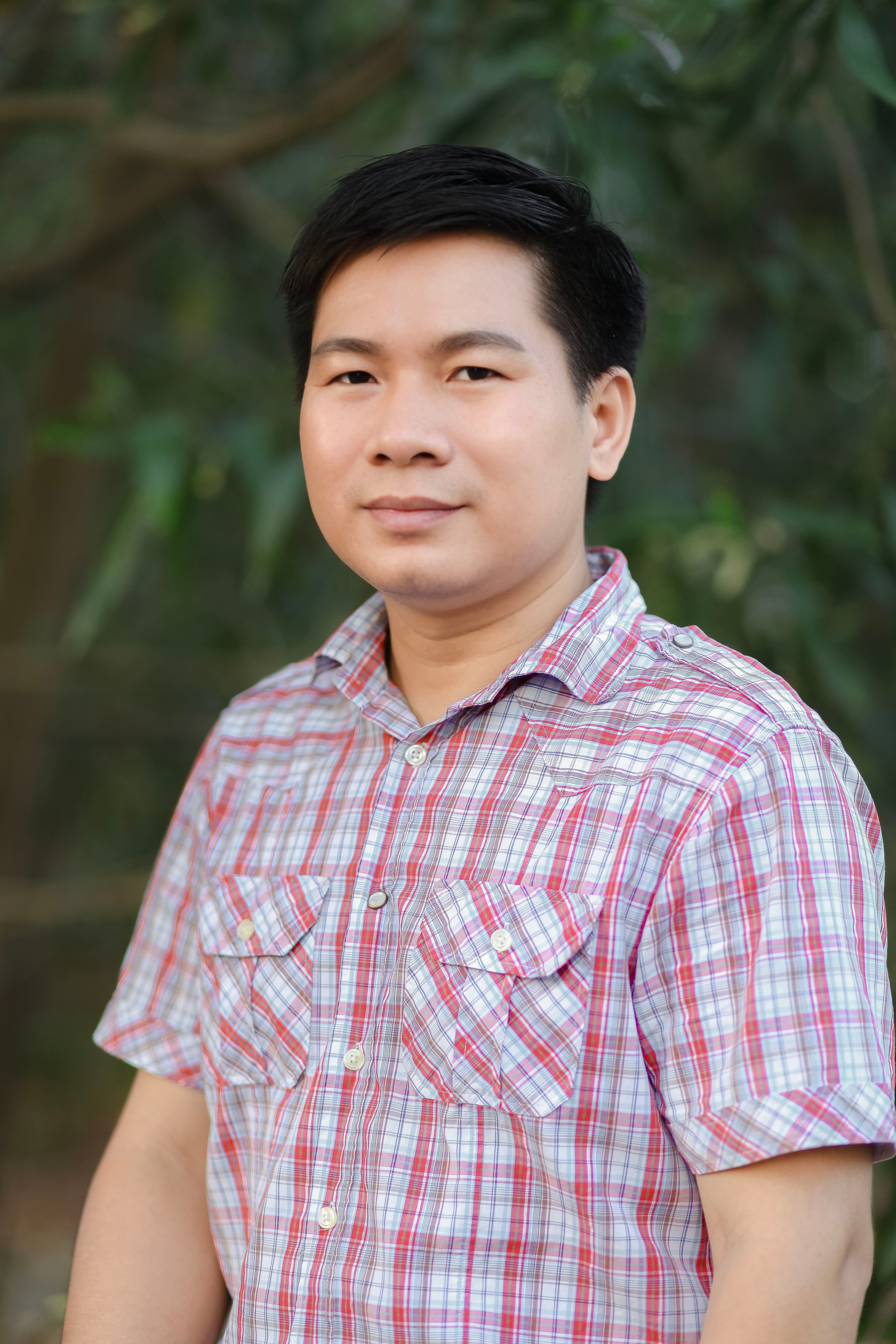 A portrait of a man standing outdoors in a casual shirt, looking into the camera.