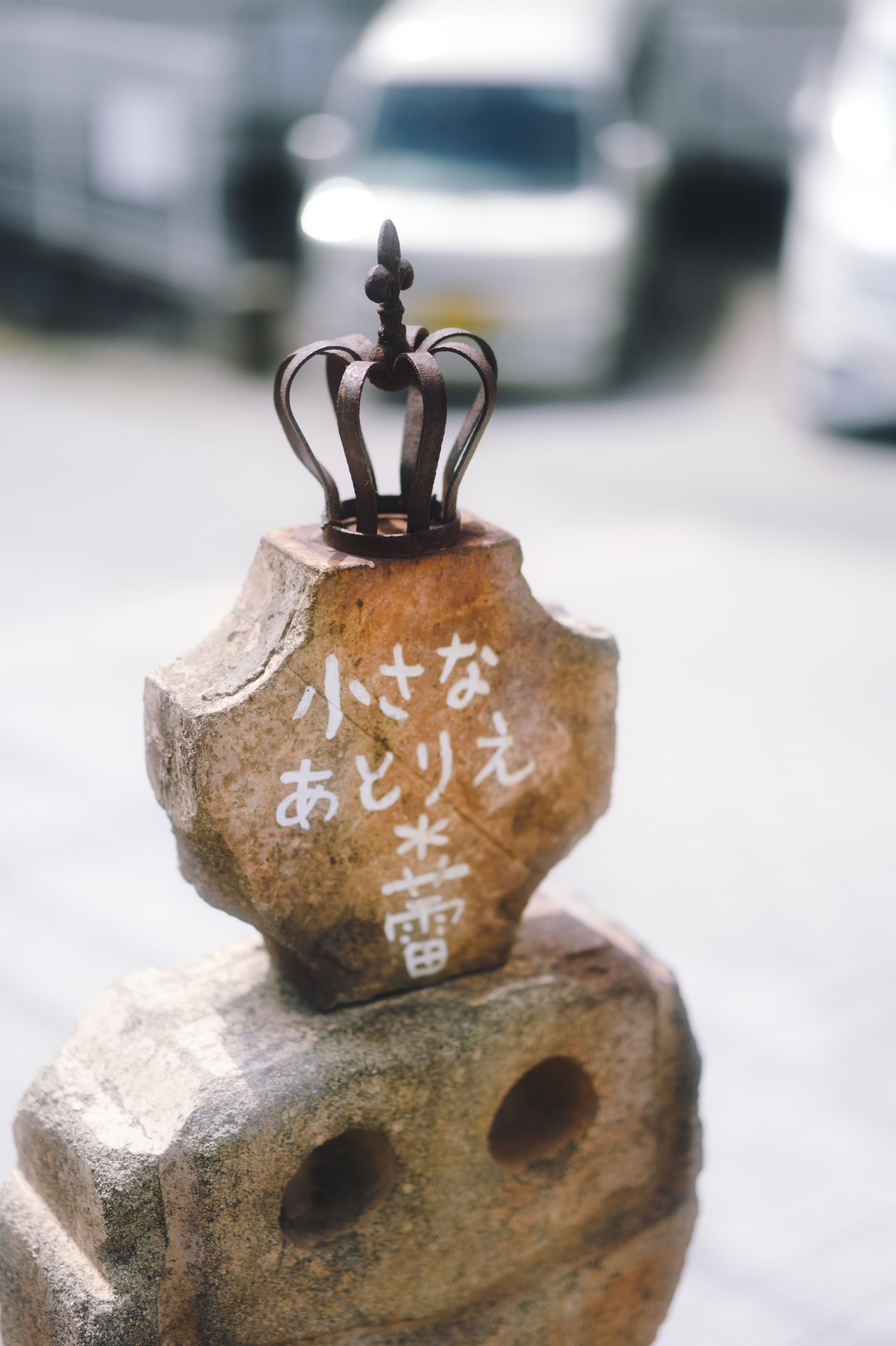 Stone marker with crown in Kobe, Japan, featuring Japanese text and artistic design.
