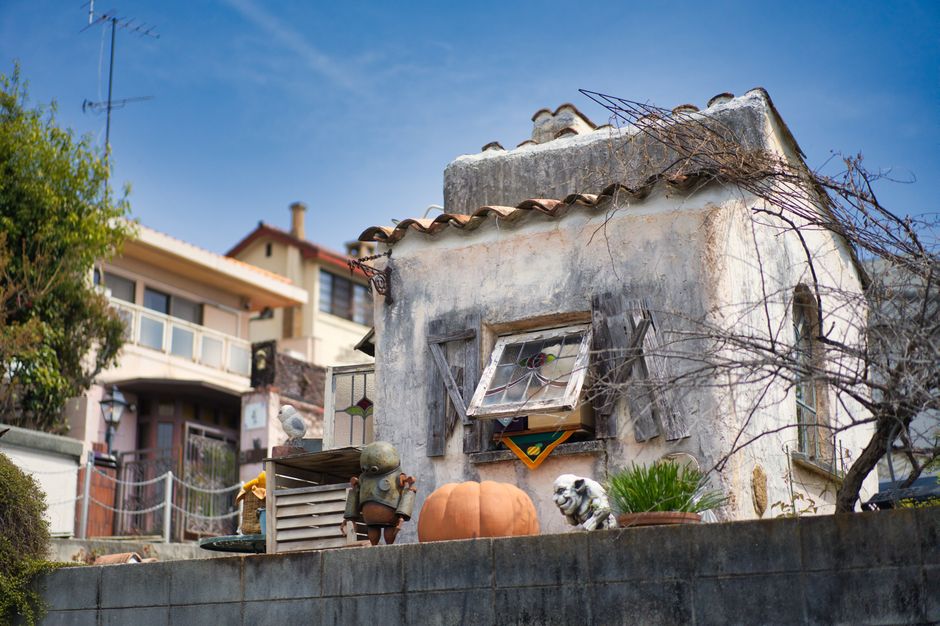 Whimsical miniature house display with rustic details, located outdoors in sunny Kobe, Japan.