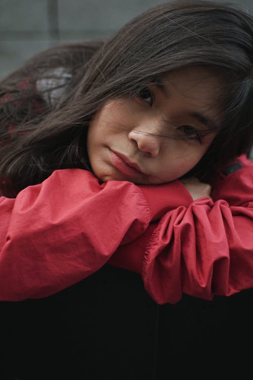 Photo of Woman Wearing Red Jacket Resting Head on Hands