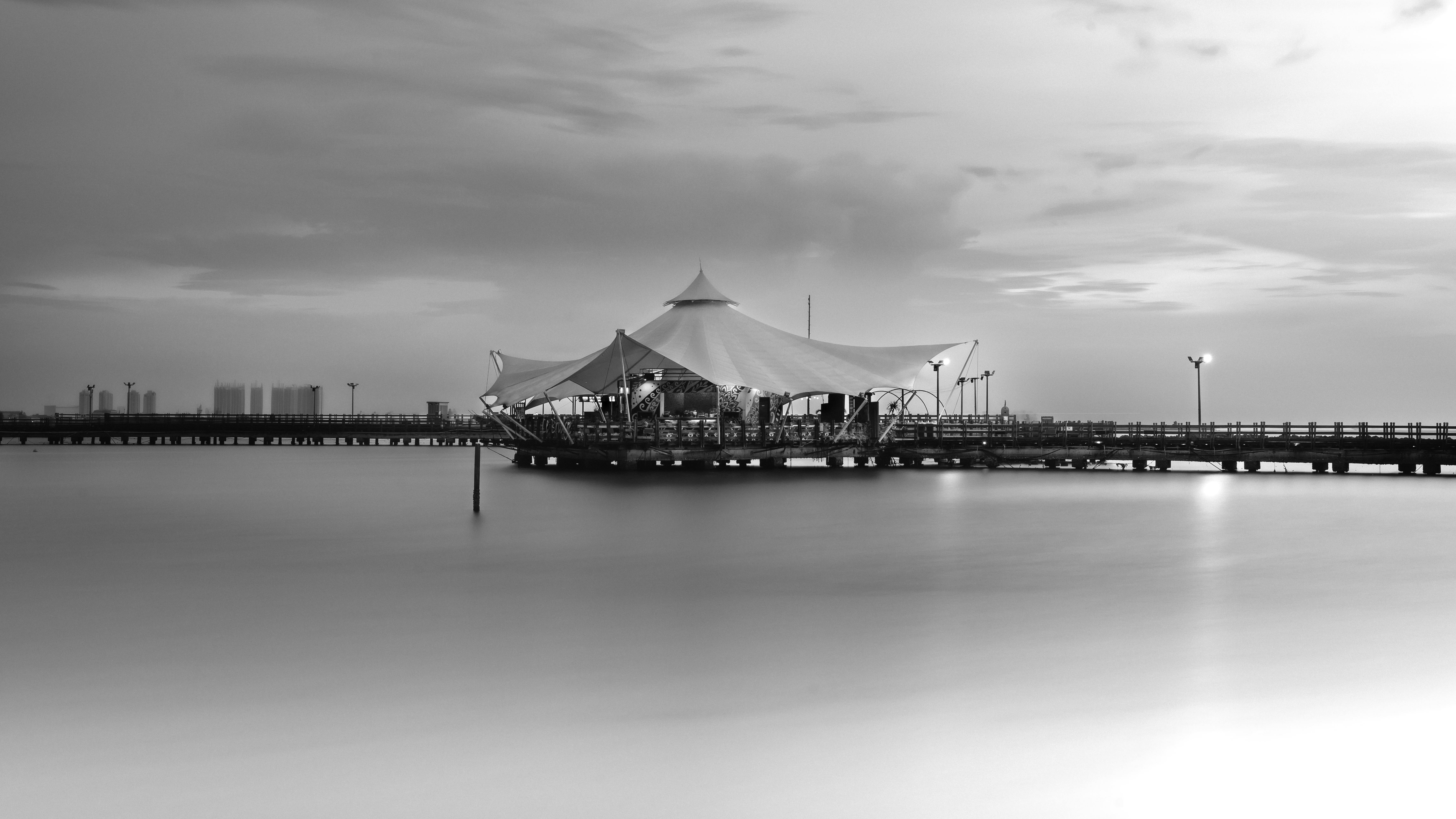 Black and white photograph of a pier with a canvas structure in Jakarta, Indonesia.