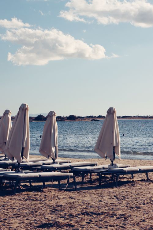 Free Peaceful beach in Naxos, Greece with closed umbrellas and serene sea view. Stock Photo