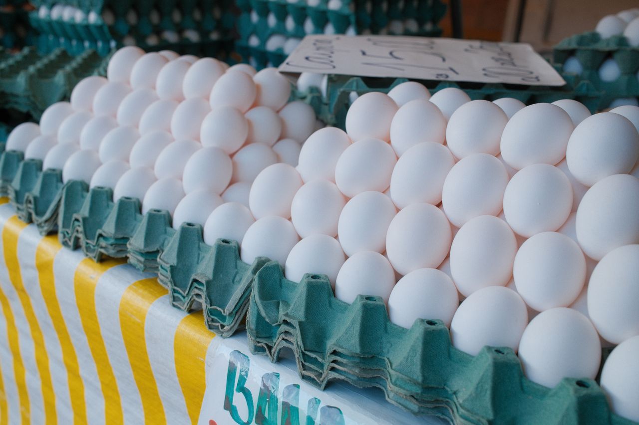 stacks of fresh white eggs on a green carton tray at a local market id