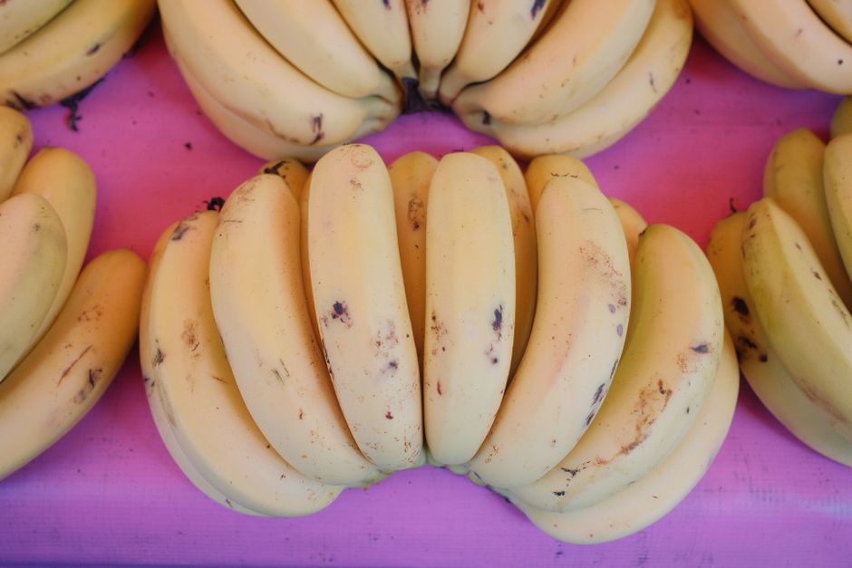 Fresh ripe yellow bananas on vibrant pink surface