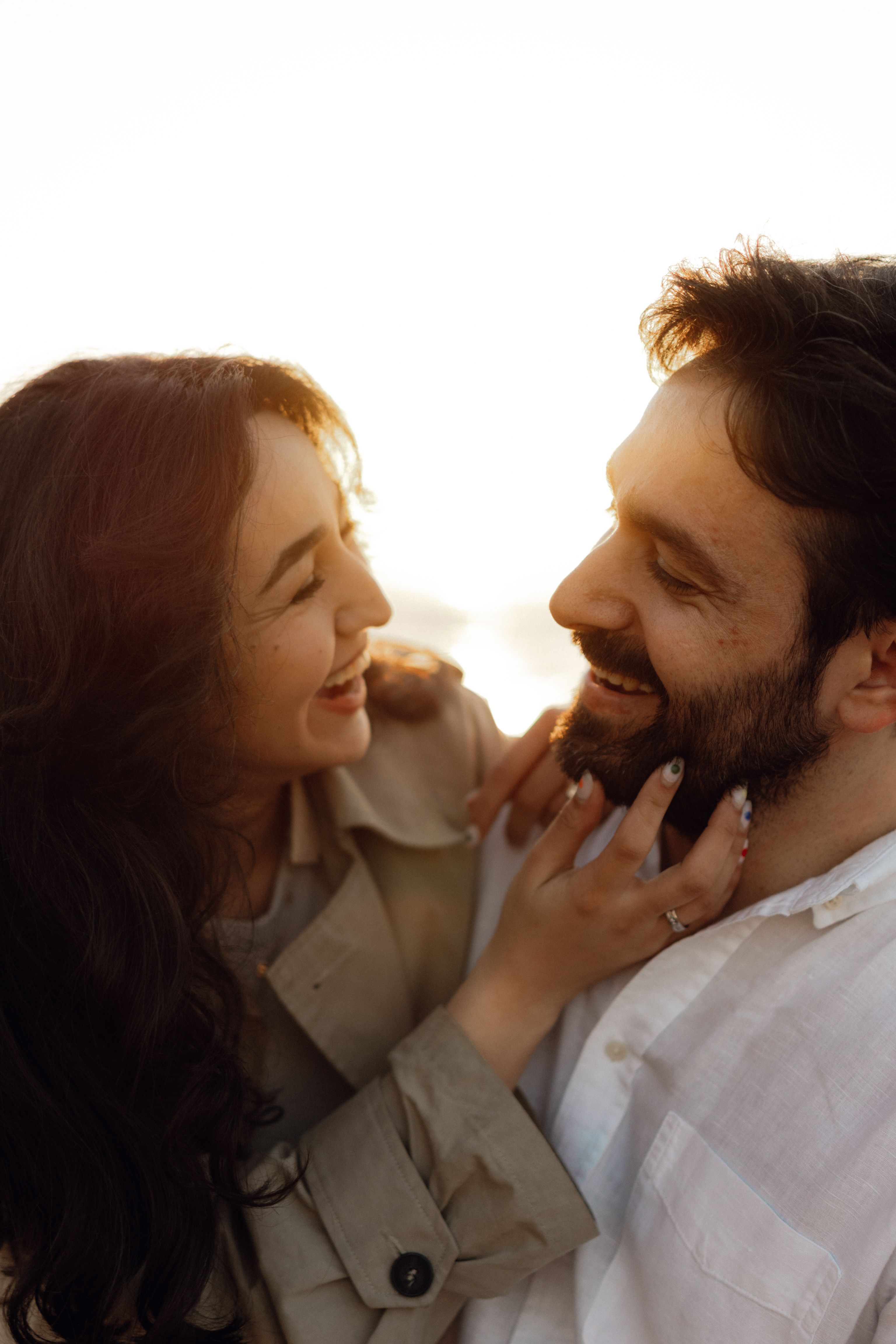 A smiling couple sharing a joyful moment outdoors at sunset.