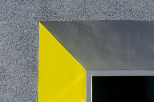 Free Close-up of a geometric architectural detail with contrasting yellow and gray walls. Stock Photo