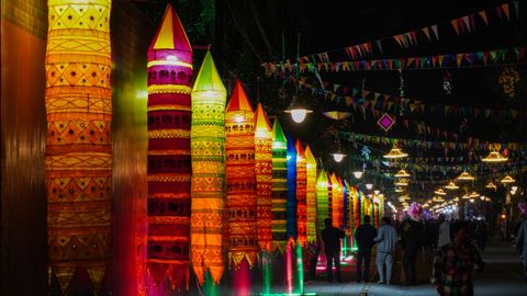 A lively festival scene with vibrant lanterns and decorations illuminated at night, creating a festive atmosphere.