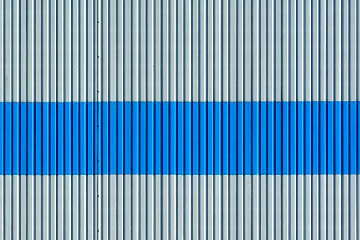 Abstract view of a corrugated metal wall with blue and grey stripes.