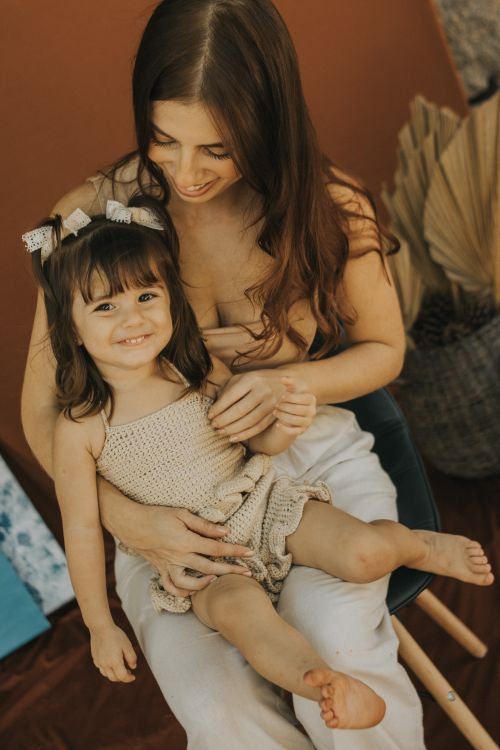 Free A joyful mother holding her daughter, both smiling warmly in an intimate indoor setting. Stock Photo