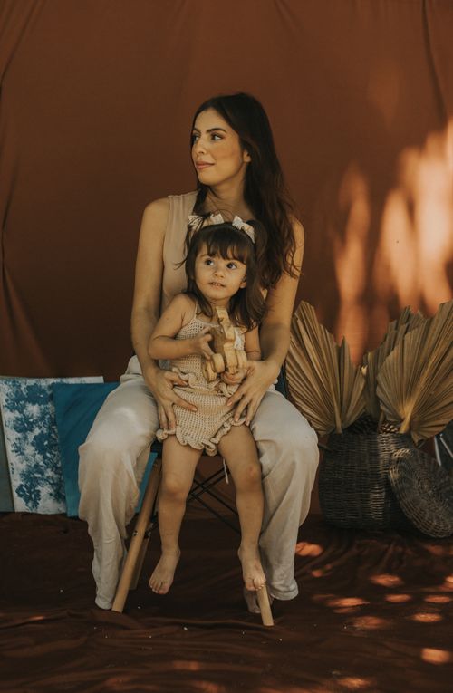 Free A mother holding her child seated on a chair with rustic decor and warm lighting. Stock Photo