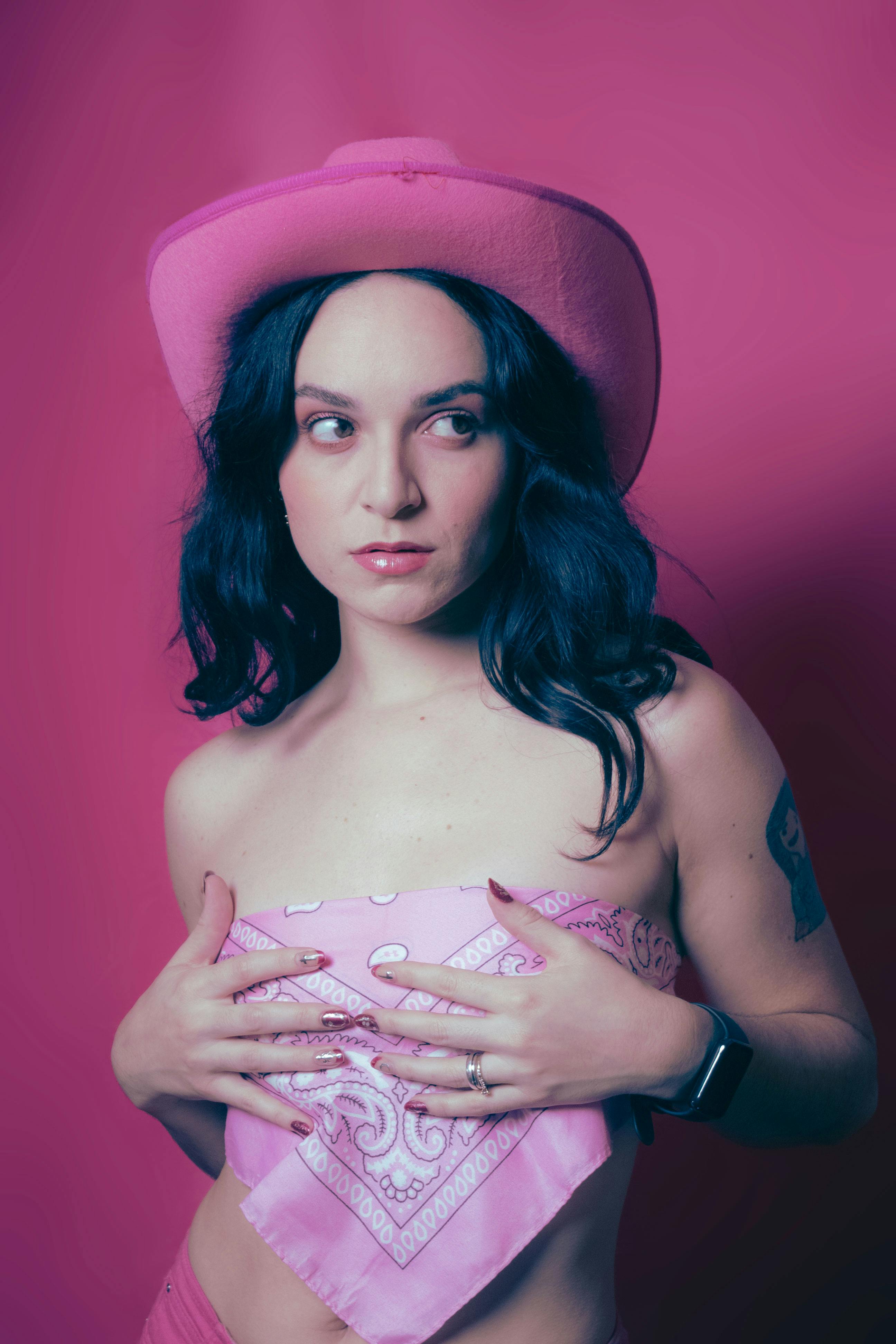 Artistic portrait of a woman in pink cowgirl attire with a vibrant background, capturing bold fashion.