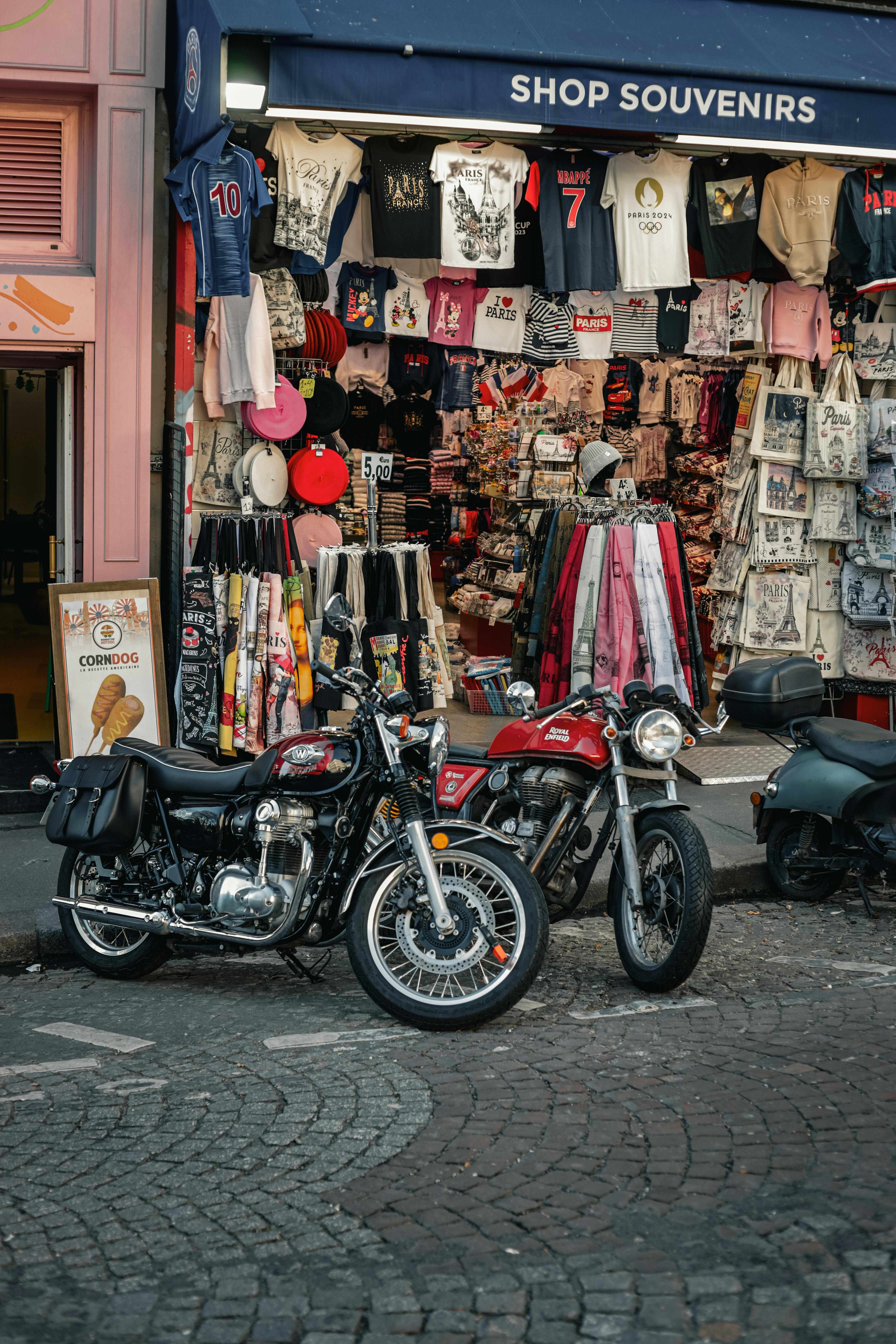 Free Vintage motorbikes parked on a cobblestone street in front of a Paris souvenir shop. Stock Photo