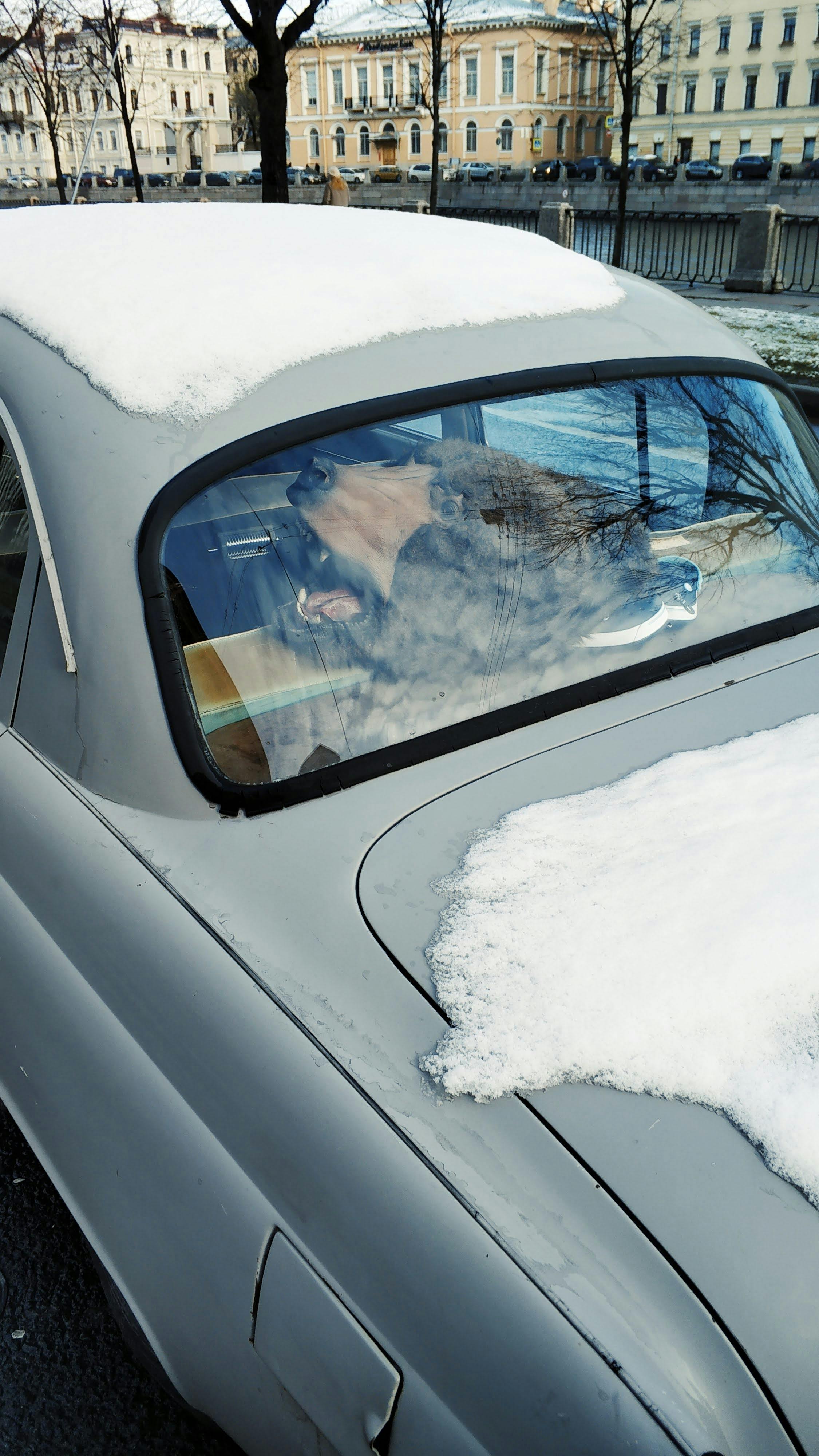 冬日里，一辆灰色的老爷车在欧洲的街道上，车身部分被雪覆盖