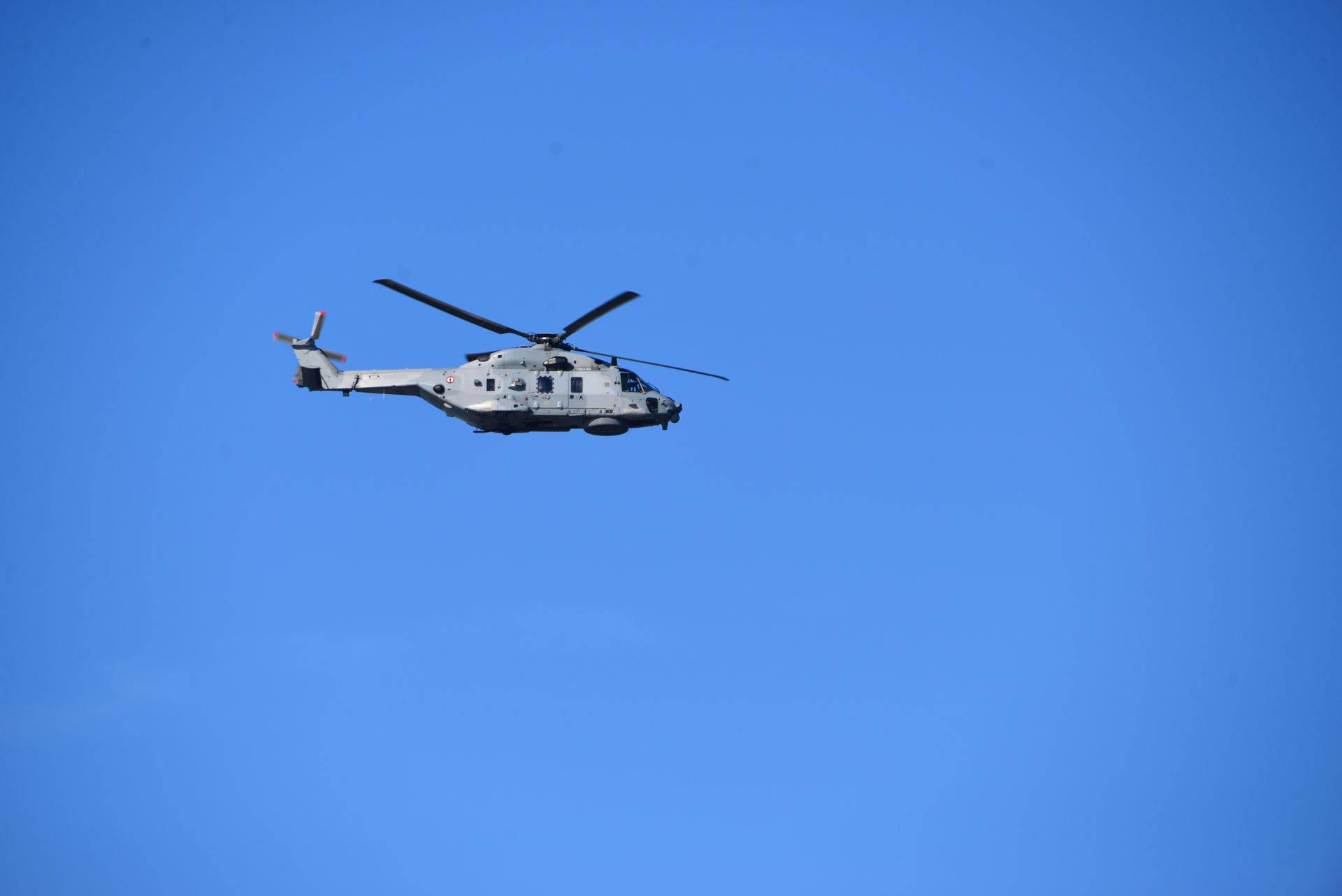 A military helicopter flies against a clear blue sky, showcasing advanced aviation technology.