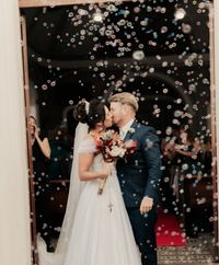 A newlywed couple shares a kiss as bubbles float around, creating a dreamy wedding moment.