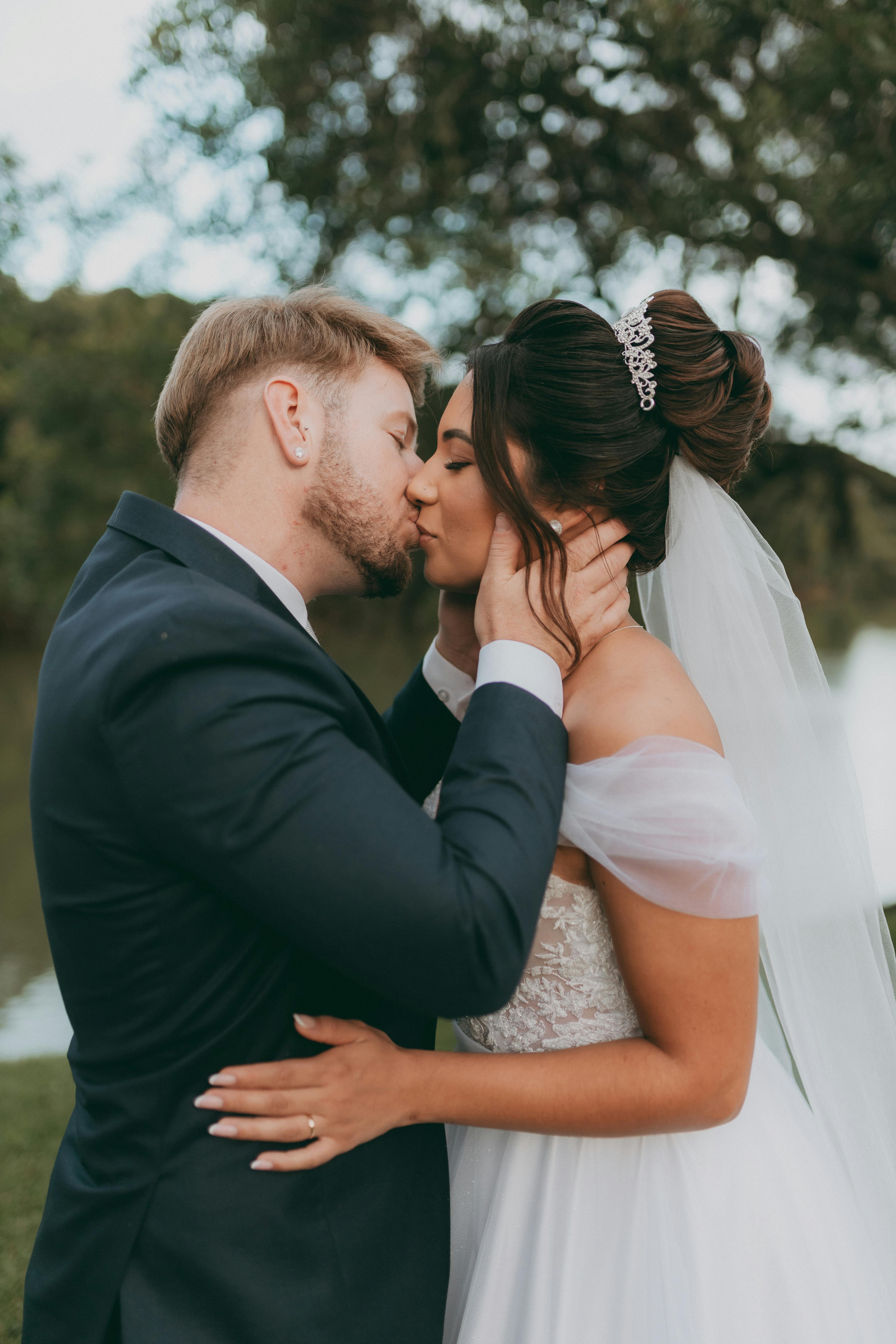 免費 優雅的新婚夫婦在寧靜的湖邊戶外親吻。 圖庫相片