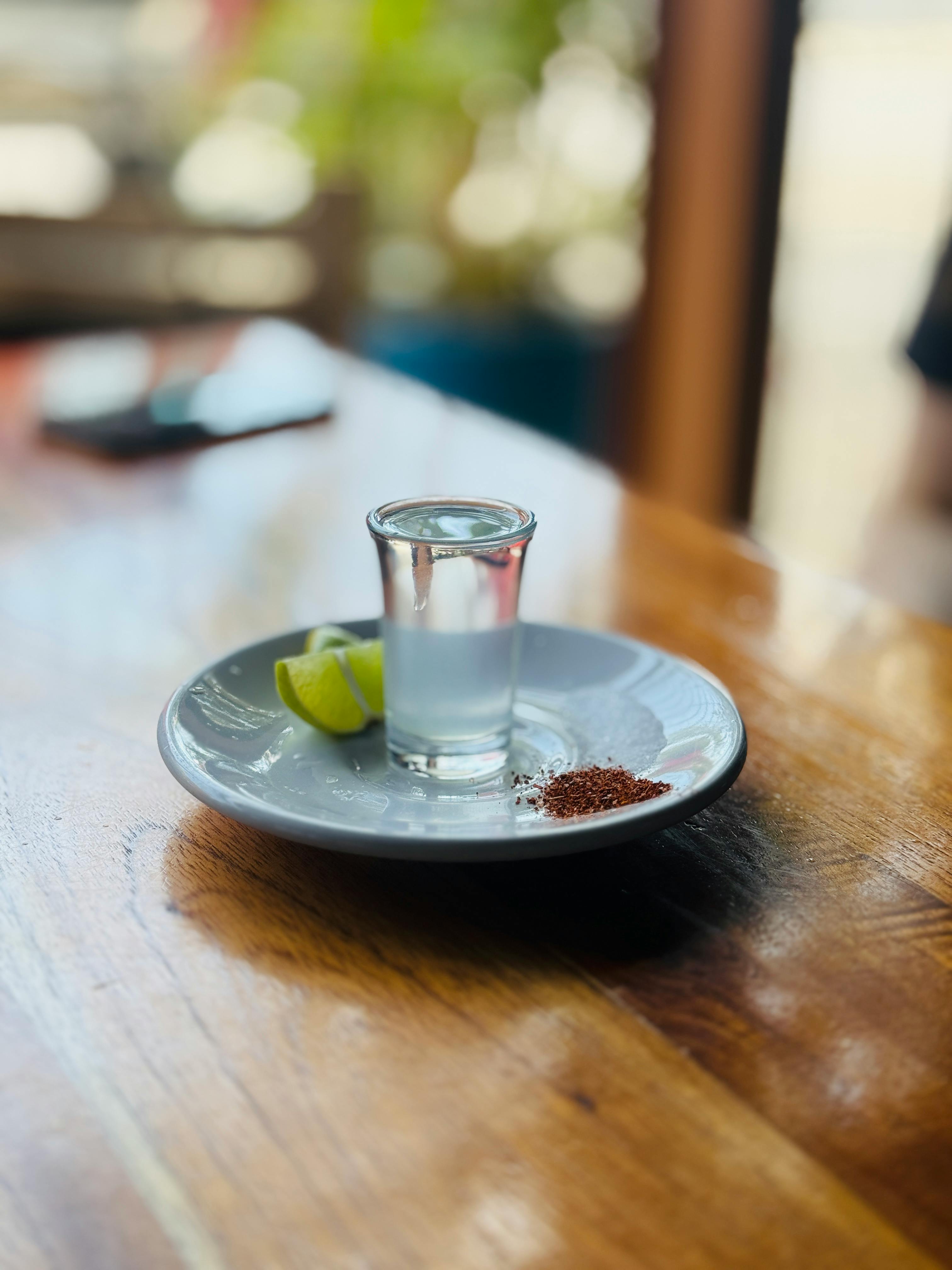 A tequila shot with lime and salt on a wooden table, perfect for a refreshing drink.