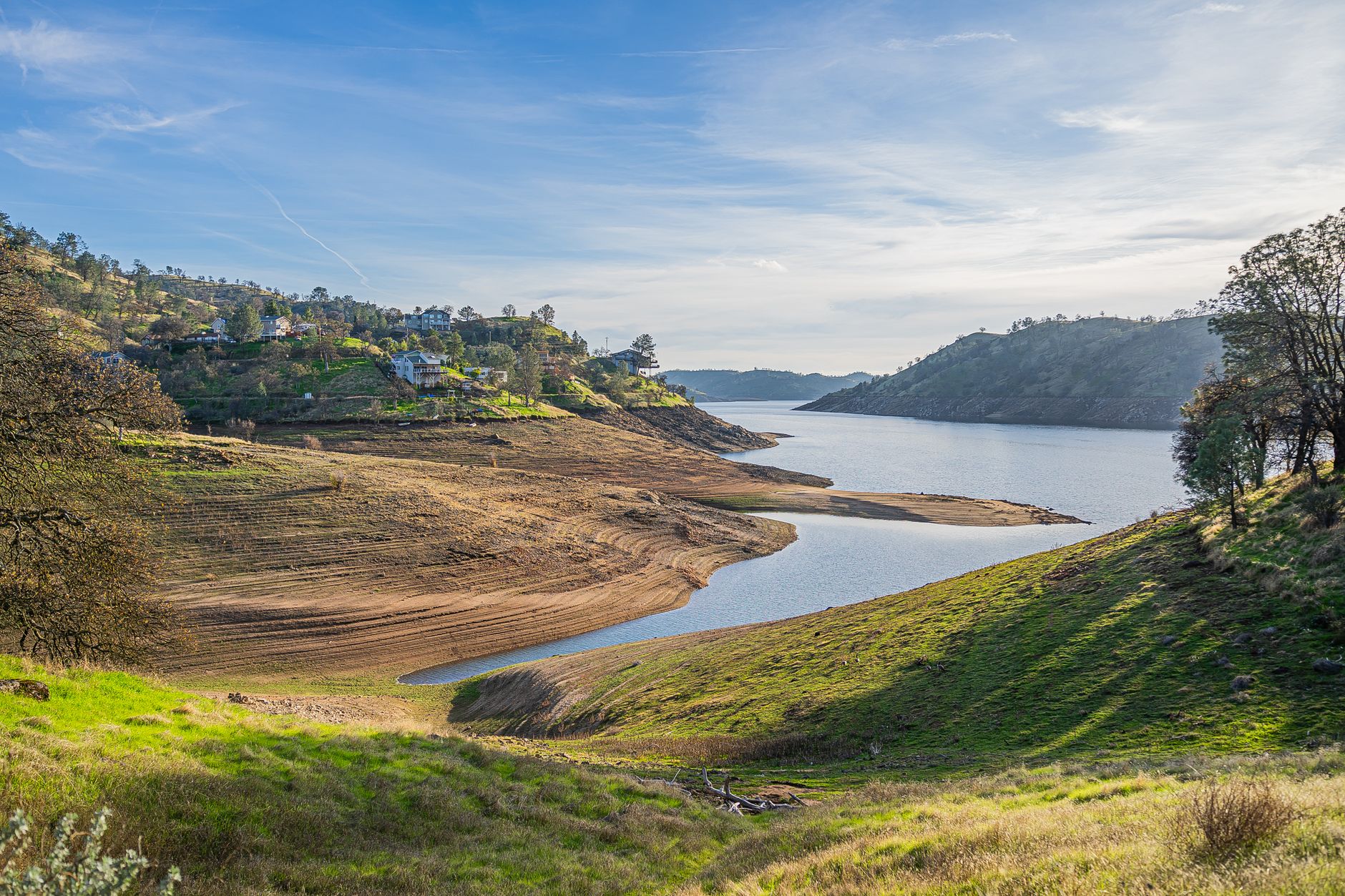Serene landscape of Millerton Lake with clear skies and rolling hills in California.