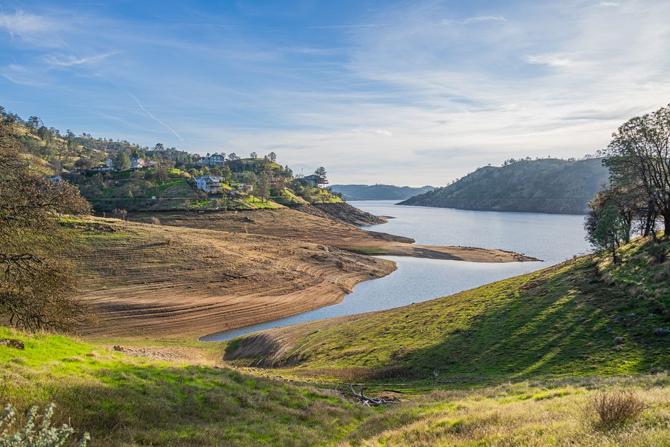 Serene landscape of Millerton Lake with clear skies and rolling hills in California.