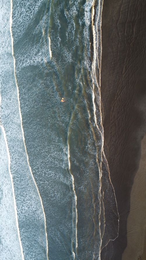Free Overhead shot of ocean waves crashing on the sandy shore in Mar del Plata, Argentina. Stock Photo