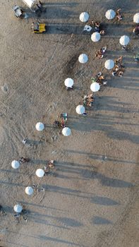 Aerial view of a sandy beach in Mar del Plata with umbrellas casting long shadows.