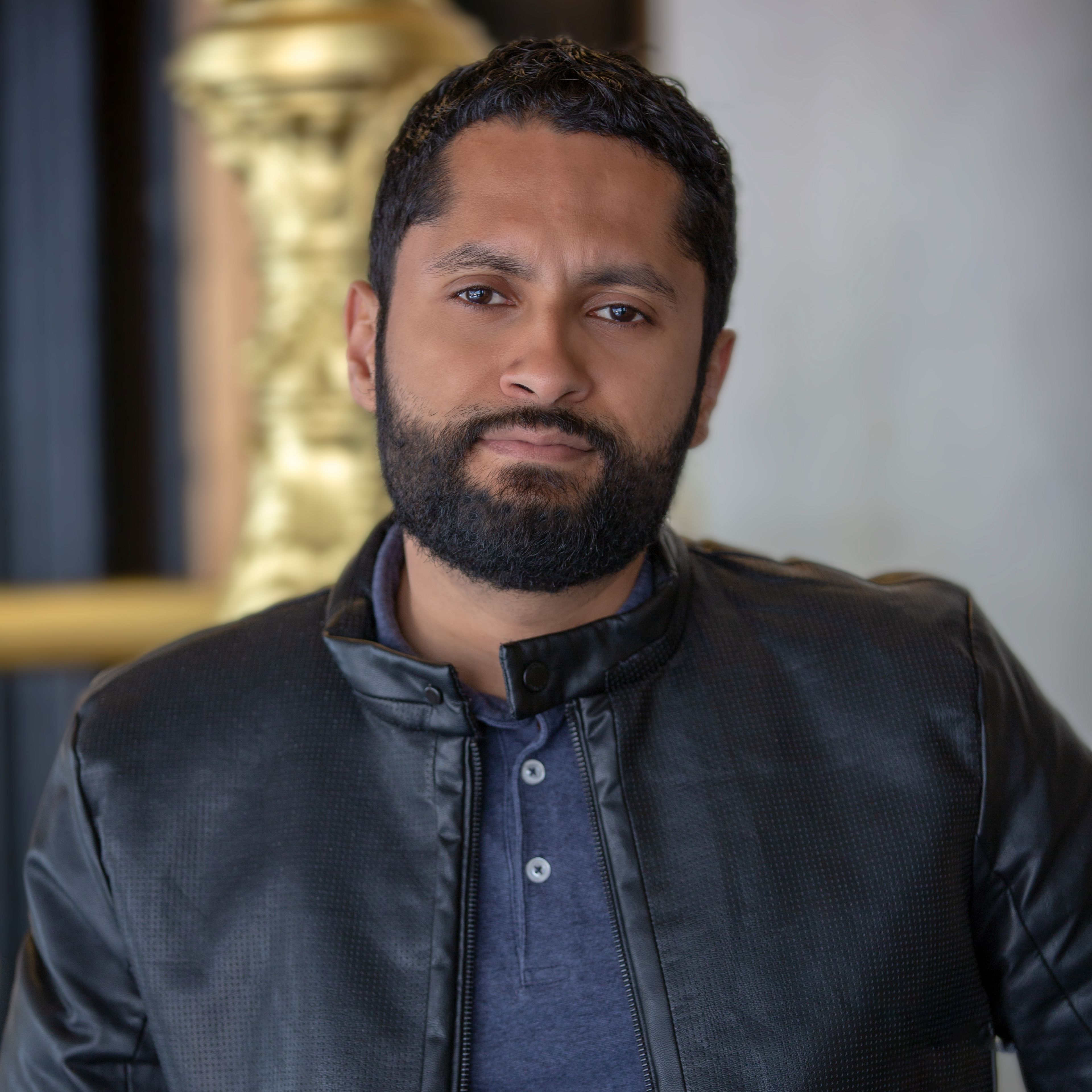 Portrait of a confident man in a leather jacket indoors, showcasing casual fashion.