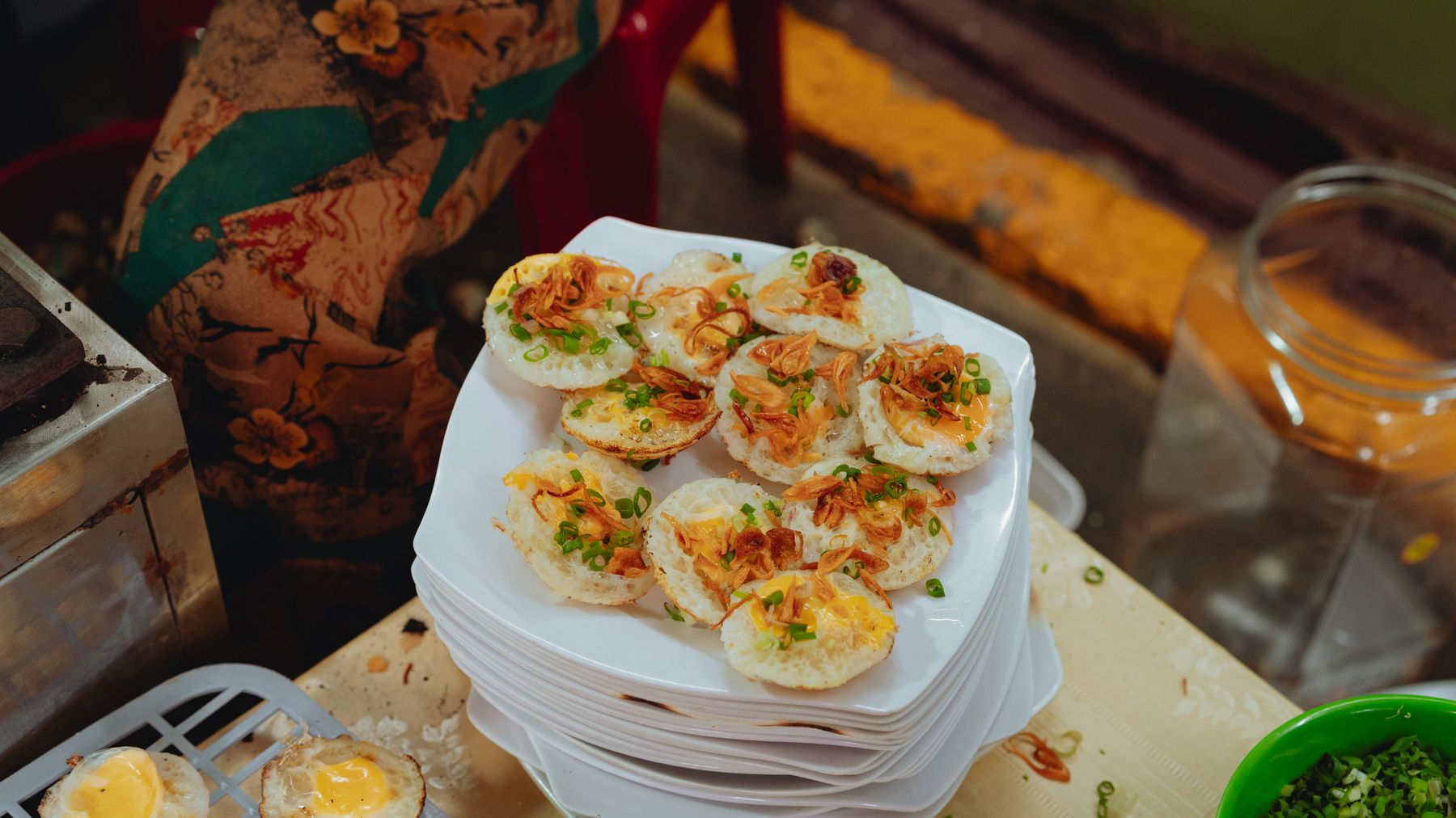 Plate of traditional bánh khọt with toppings, captured in a market setting in Bình Thuận, Vietnam.