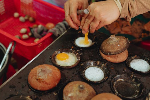 A close-up of hands cooking Vietnamese street food with eggs, showcasing a traditional culinary method in Bình Thuận.