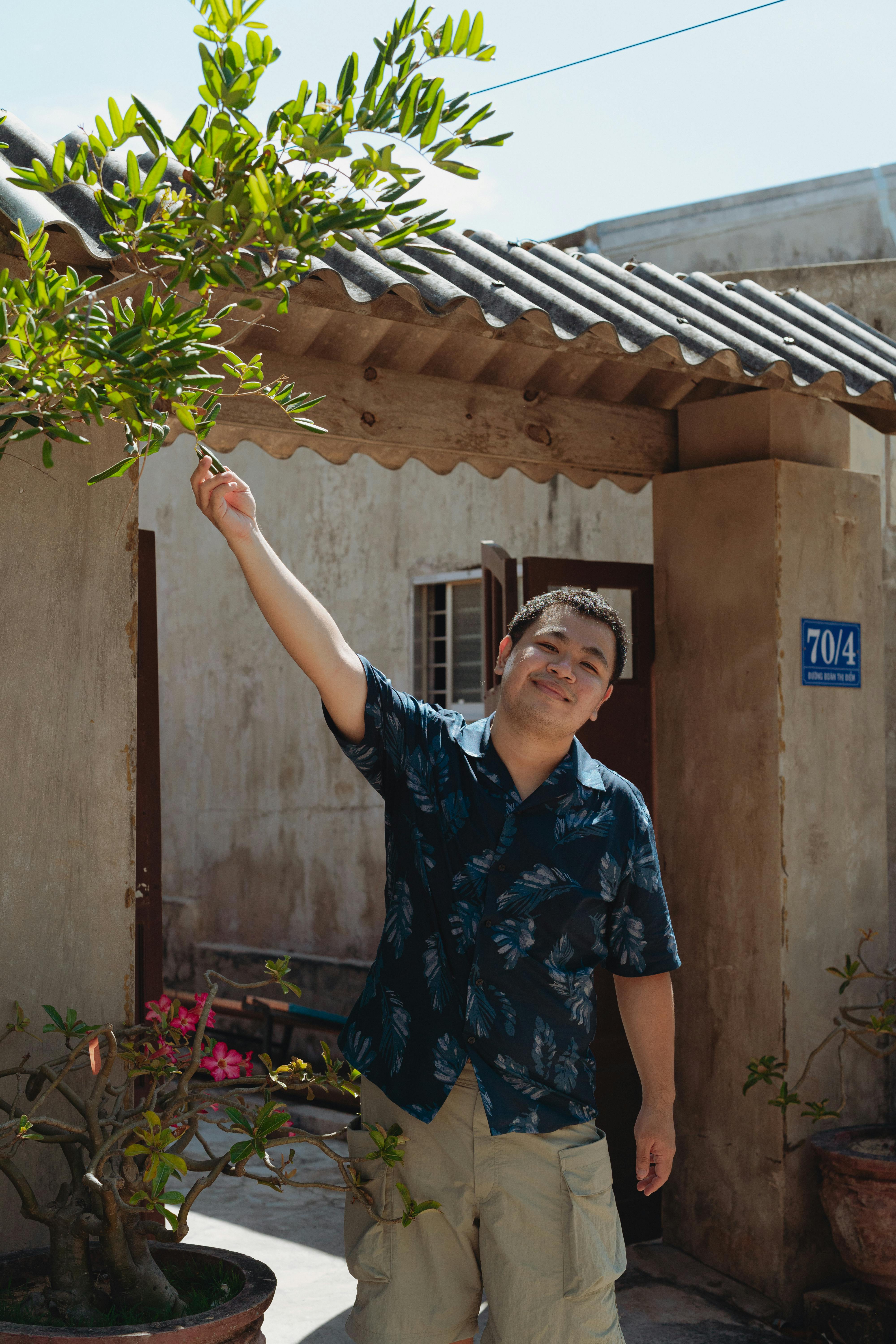 Cheerful man in a courtyard, Bình Thuận, Vietnam, under a sunny blue sky.