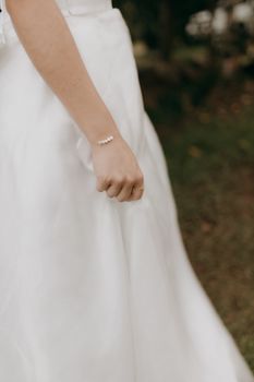Detailed shot of a bride's hand wearing a pearl bracelet, capturing wedding elegance and style.