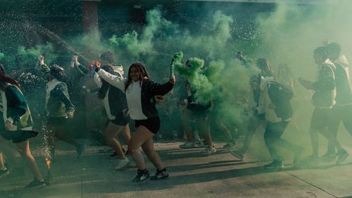 Free Energetic group of teenagers celebrating with vibrant smoke bombs outdoors. Stock Photo