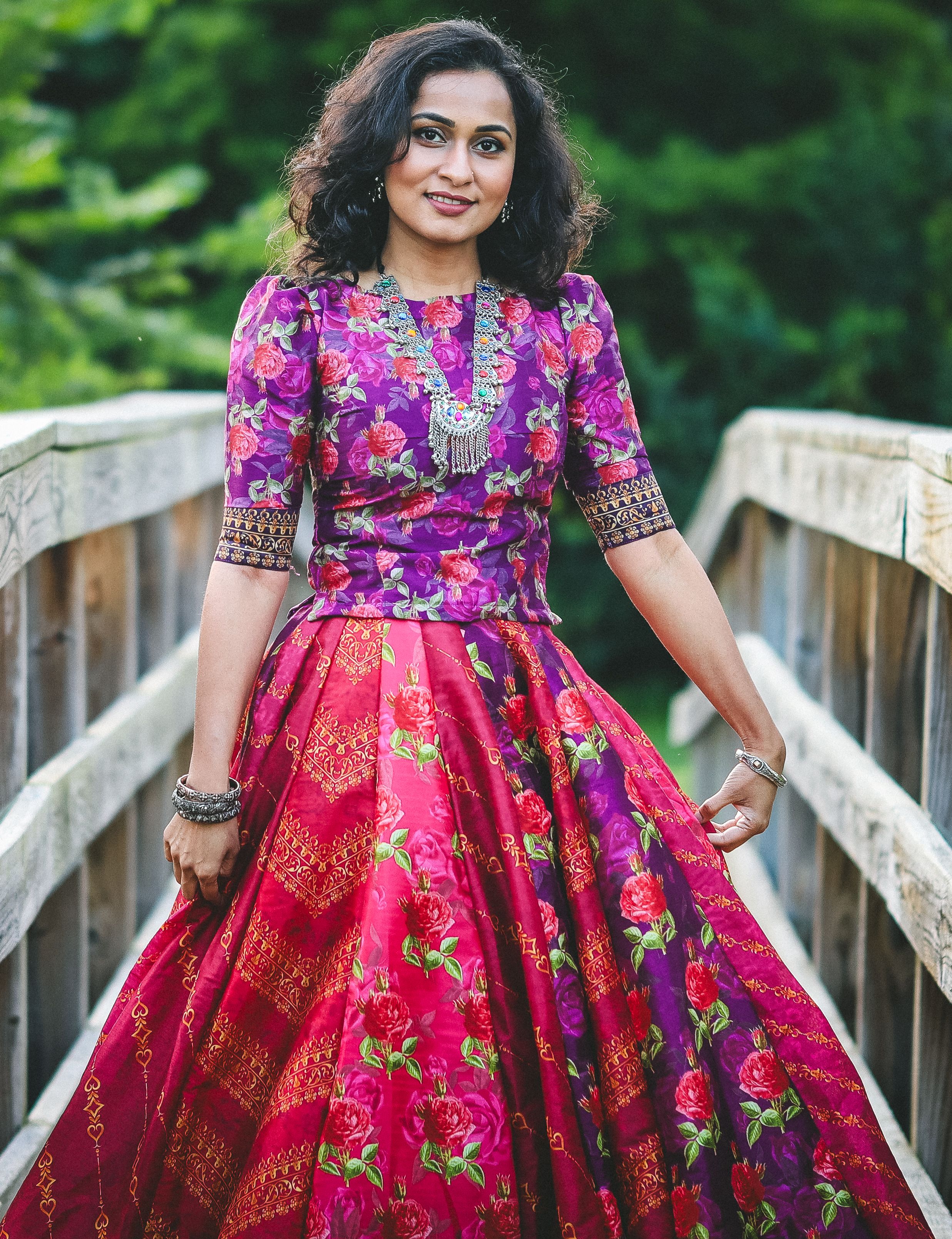 Elegant Woman in Vibrant Floral Dress on Bridge · Free Stock Photo