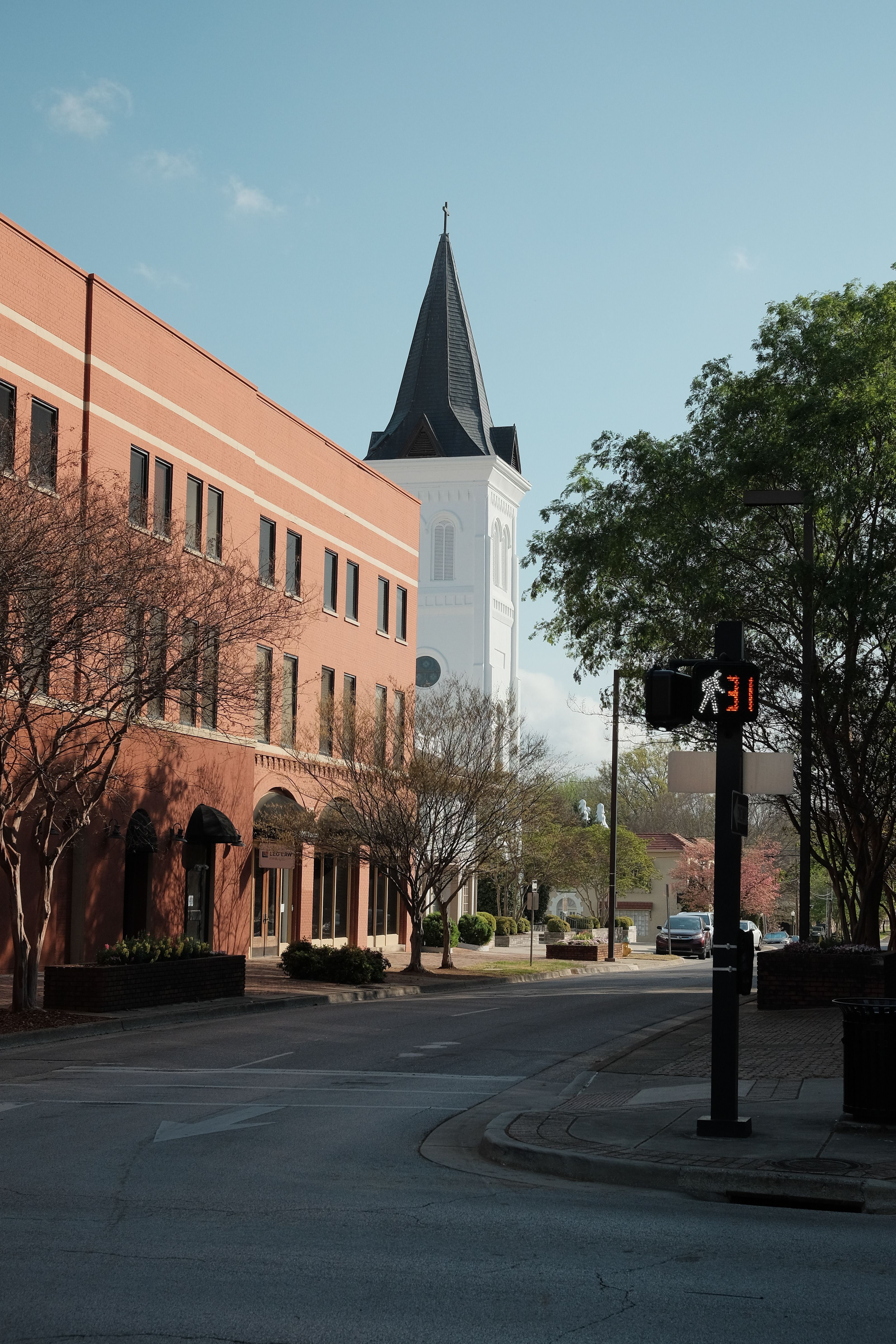Historic brick church with a tall steeple on a city street