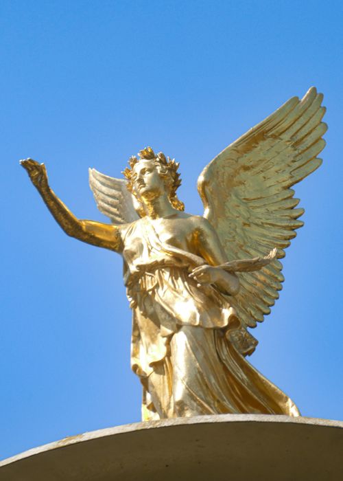 Free A golden angel statue with wings spread wide against a vibrant blue sky, symbolizing peace and serenity. Stock Photo