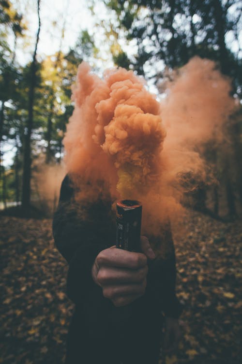 Person Holding Orange Smoke Bomb