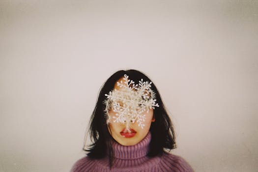 Artistic portrait of woman in winter attire with snowflake covering face, creating a unique and conceptual effect.
