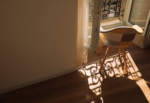 A warm sunlit corner with an elegant chair and intricate window shadows.