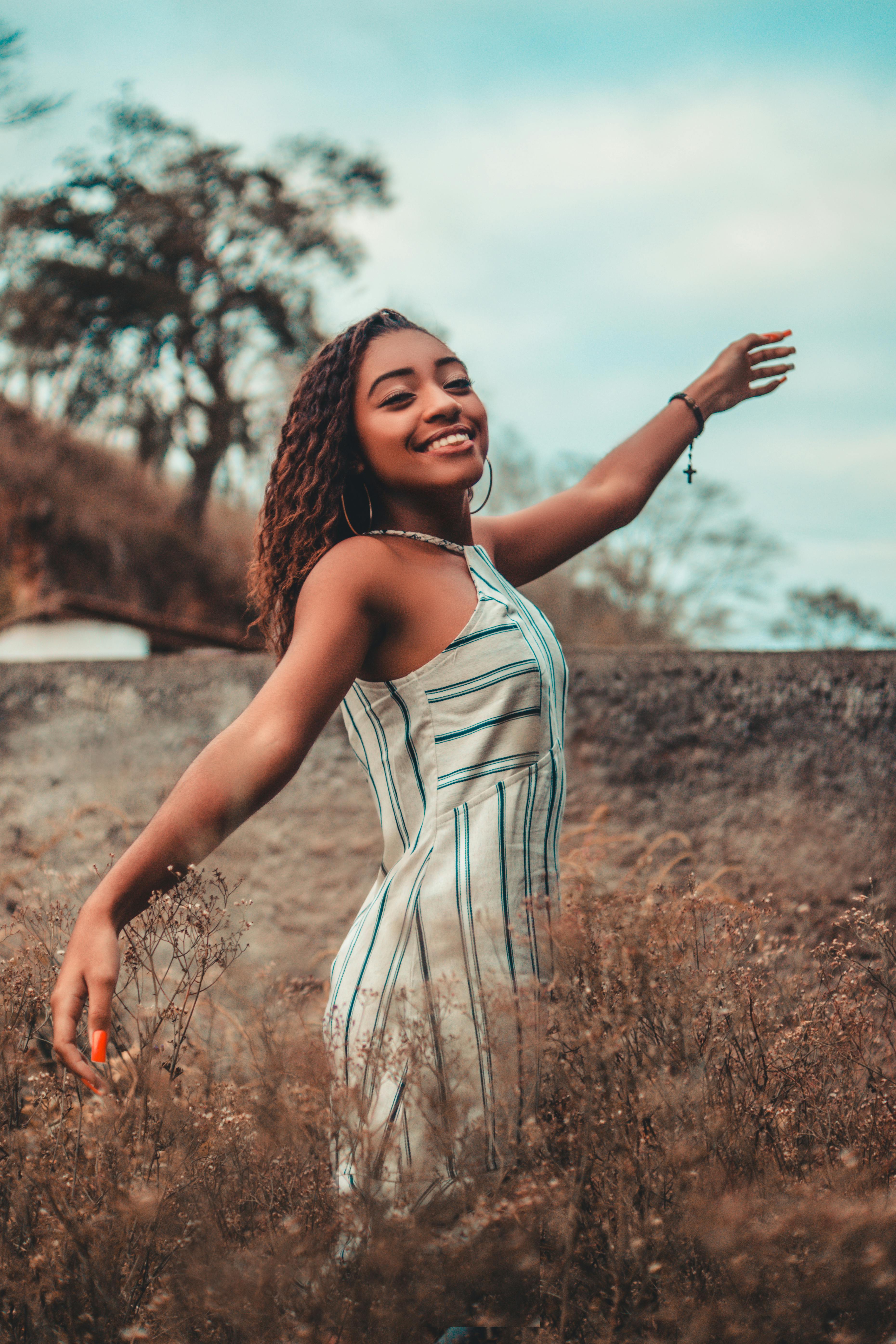 Free Woman Wearing Sleeveless Dress Standing on Grass Field Stock Photo