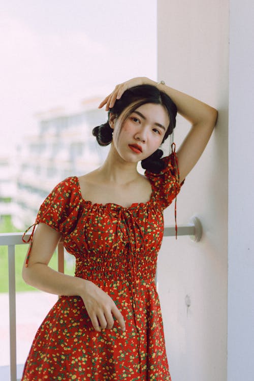 Woman Wearing Red Dress While Leaning on Wall