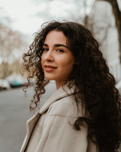 A Beautiful Woman in Curly Hair Smiling at the Camera · Free Stock Photo