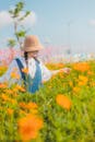 一位戴着遮阳帽的女子，在蓝天下享受着生机勃勃的花田