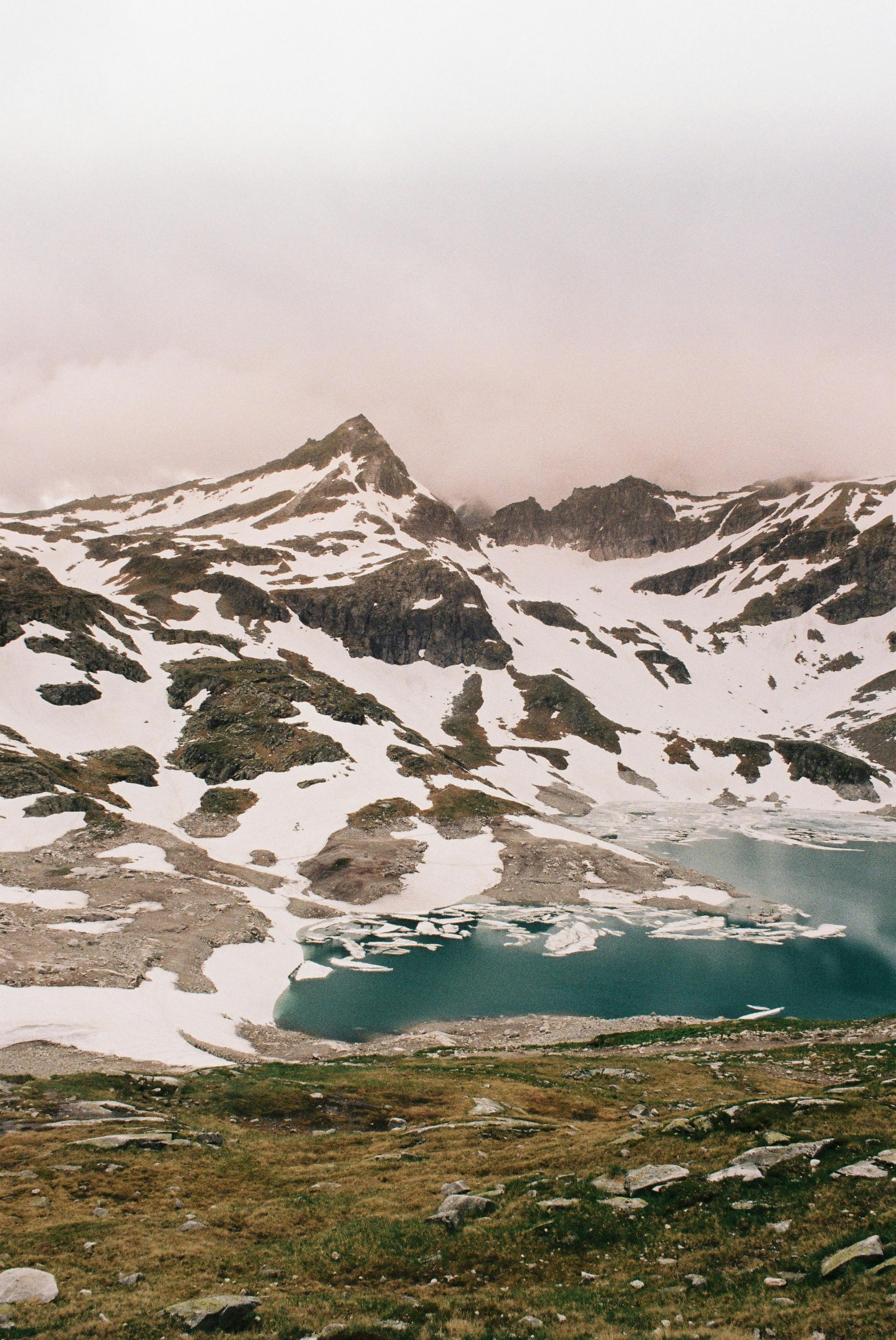 A stunning snowy mountain scene with a turquoise lake and rocky terrain.