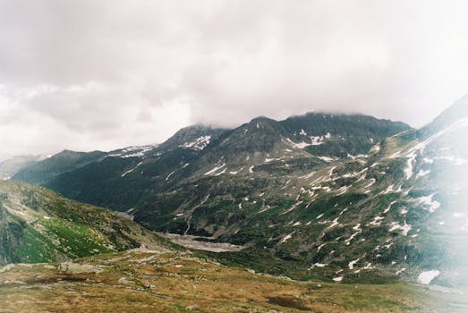 Dramatic view of the snow-capped mountains with lush greenery and rugged terrain.