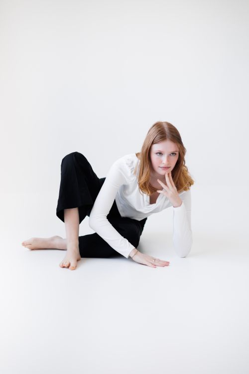 Free Elegant young woman posing in minimalist attire on a white background. Stock Photo
