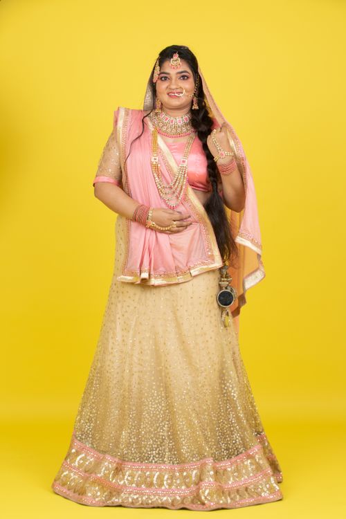 Free Portrait of a woman in Indian traditional dress with jewelry on a vibrant yellow backdrop. Stock Photo