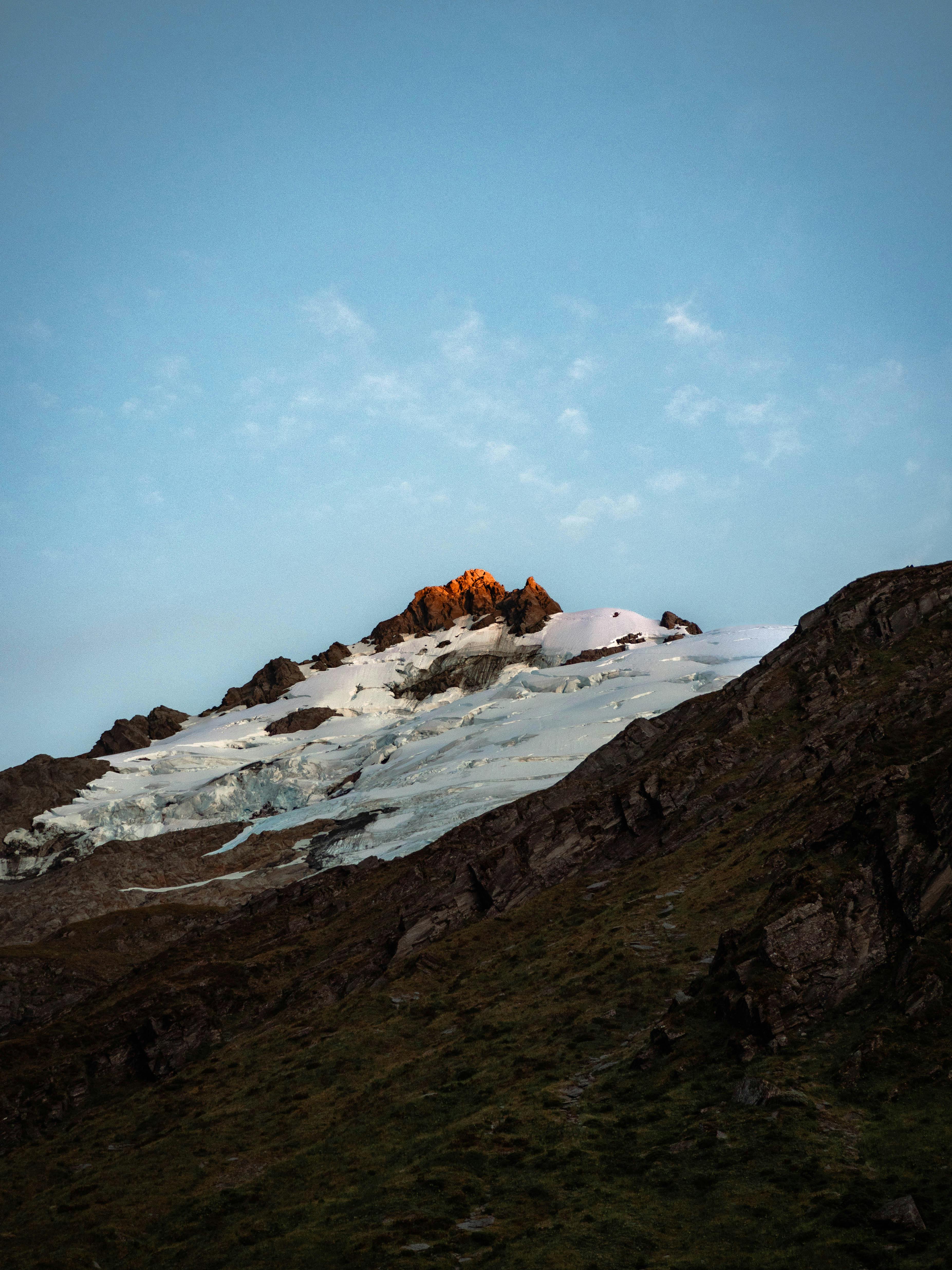 A breathtaking view of a mountain peak with alpenglow at sunrise, showcasing natural beauty.