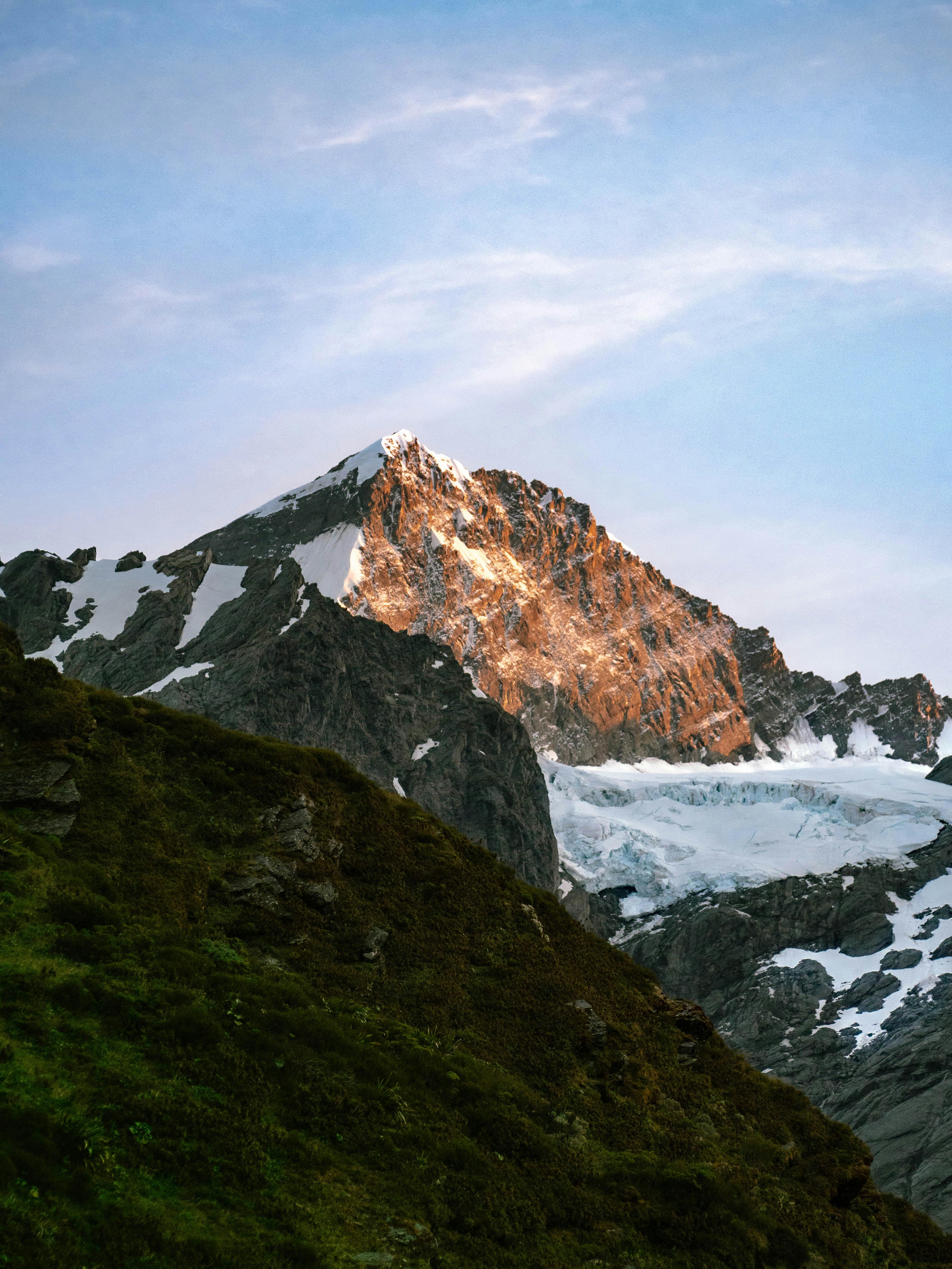 Stunning view of a snow-capped alpine mountain peak glowing in the sunrise light.