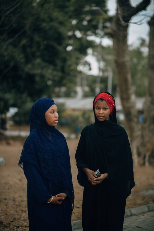 Free Two young women in elegant hijabs stand outdoors, surrounded by nature. Stock Photo
