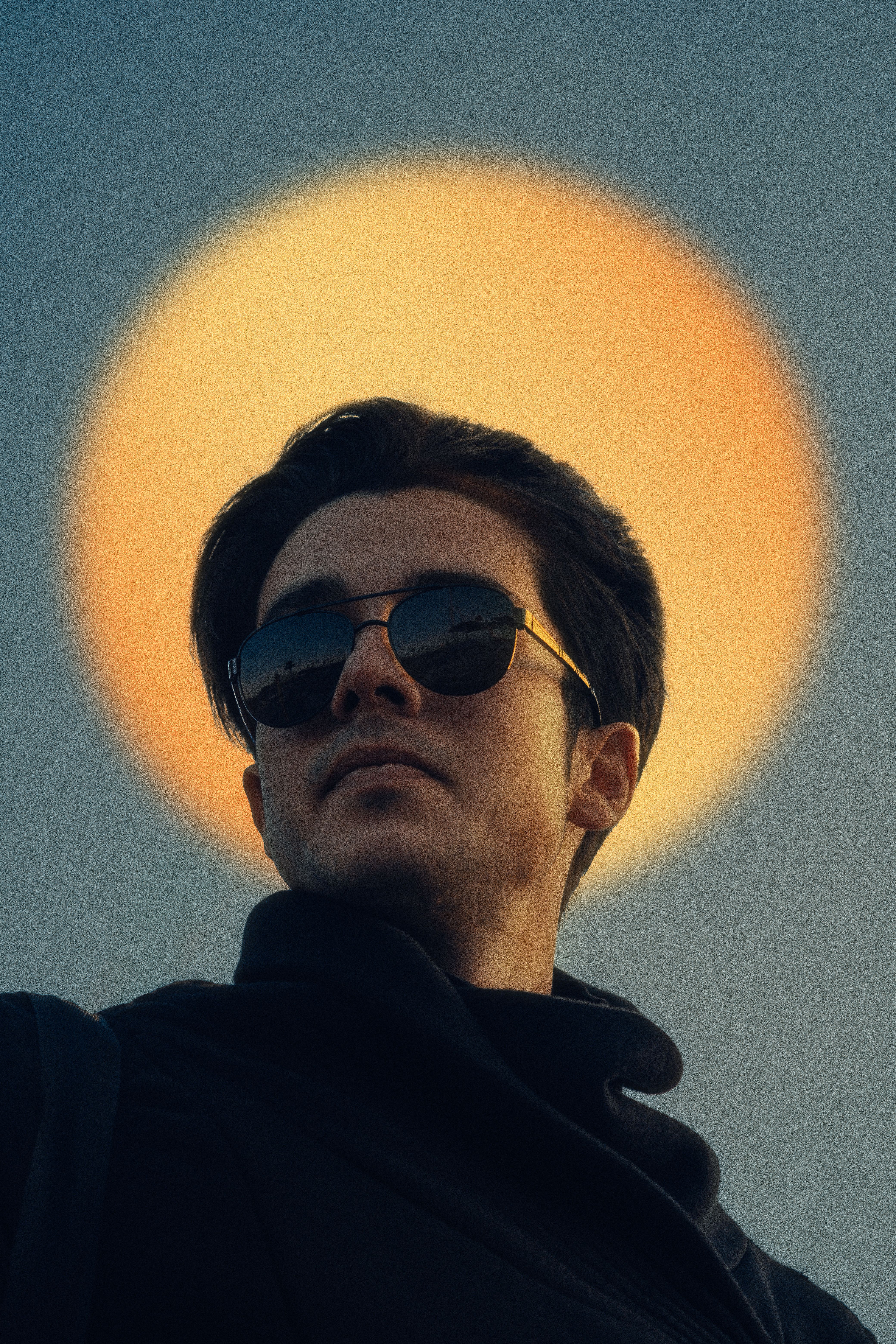 Man wearing sunglasses with a glowing halo effect in the background, creating a modern, artistic look.