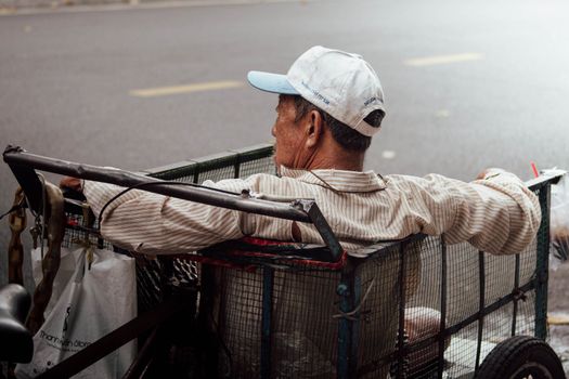 An elderly street vendor sits resting on his cart in Ho Chi Minh City, Vietnam.